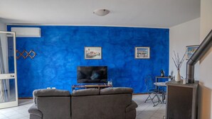 Un salon avec un mur bleu, un canapé gris, un téléviseur à écran plat et une cheminée.