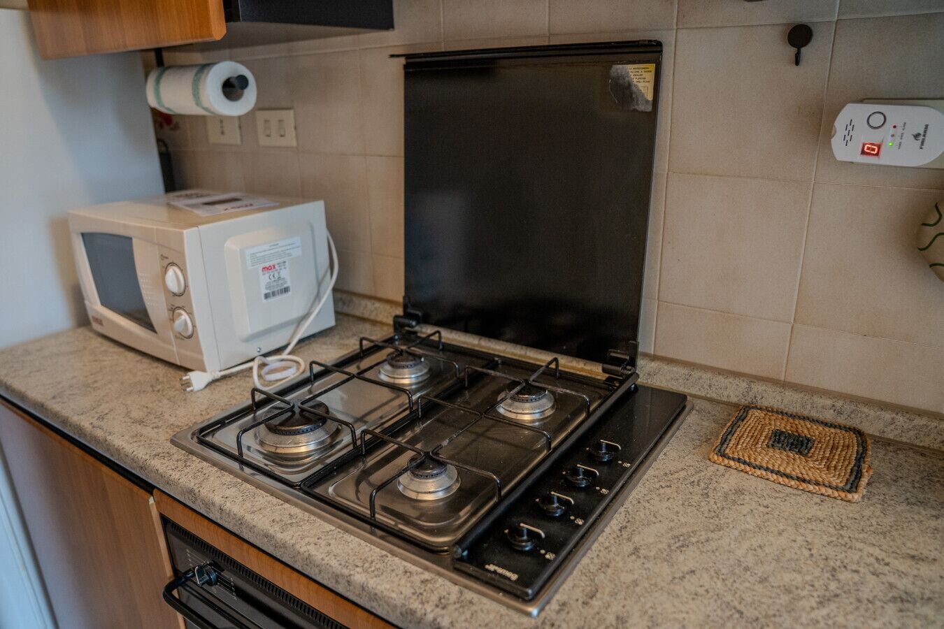 A kitchen with a gas stove, a microwave, and a refrigerator.