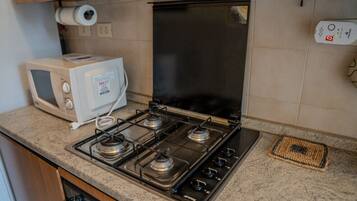 A kitchen with a gas stove, a microwave, and a refrigerator.