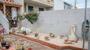 Une cour agrémentée de divers pots de plantes, d’une petite fontaine et d’un chemin en briques.