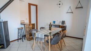 Un coin repas comprenant une table en verre, quatre chaises, un buffet en bois et une horloge murale.