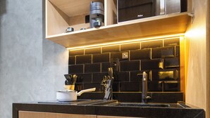 Eine moderne Küche mit integriertem Backofen und Mikrowelle, Holzschränken und einer schwarzen Spritzschutzwand.