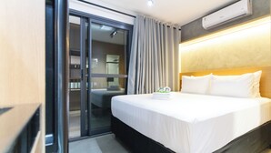 Ein Hotelzimmer mit Bett, einer Schiebetür zum Balkon und einer Klimaanlage an der Wand.