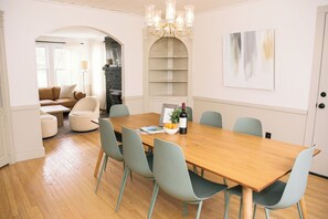 A dining area with a wooden table, six chairs, a chandelier, and a wall-mounted shelf. - 2 Min Walk to Windham Town | Hot Tub | Fire Pit (Windham)