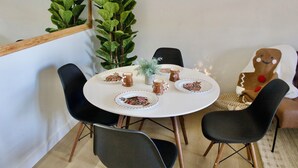 A round dining table with a white tablecloth, surrounded by black chairs. There are plates with gingerbread man designs, and a small potted plant in the center. - Resort Condo NEXT to Ski Run w/ Pool & Hot tub! (Brian Head)