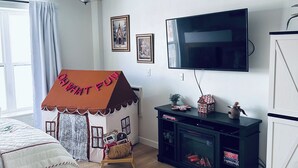 A cozy bedroom with a bed, a playhouse, a TV, and a bookshelf. - Resort Condo NEXT to Ski Run w/ Pool & Hot tub! (Brian Head)