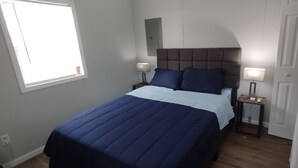 Een slaapkamer met een bed, twee nachtkastjes, een venster en een deur.