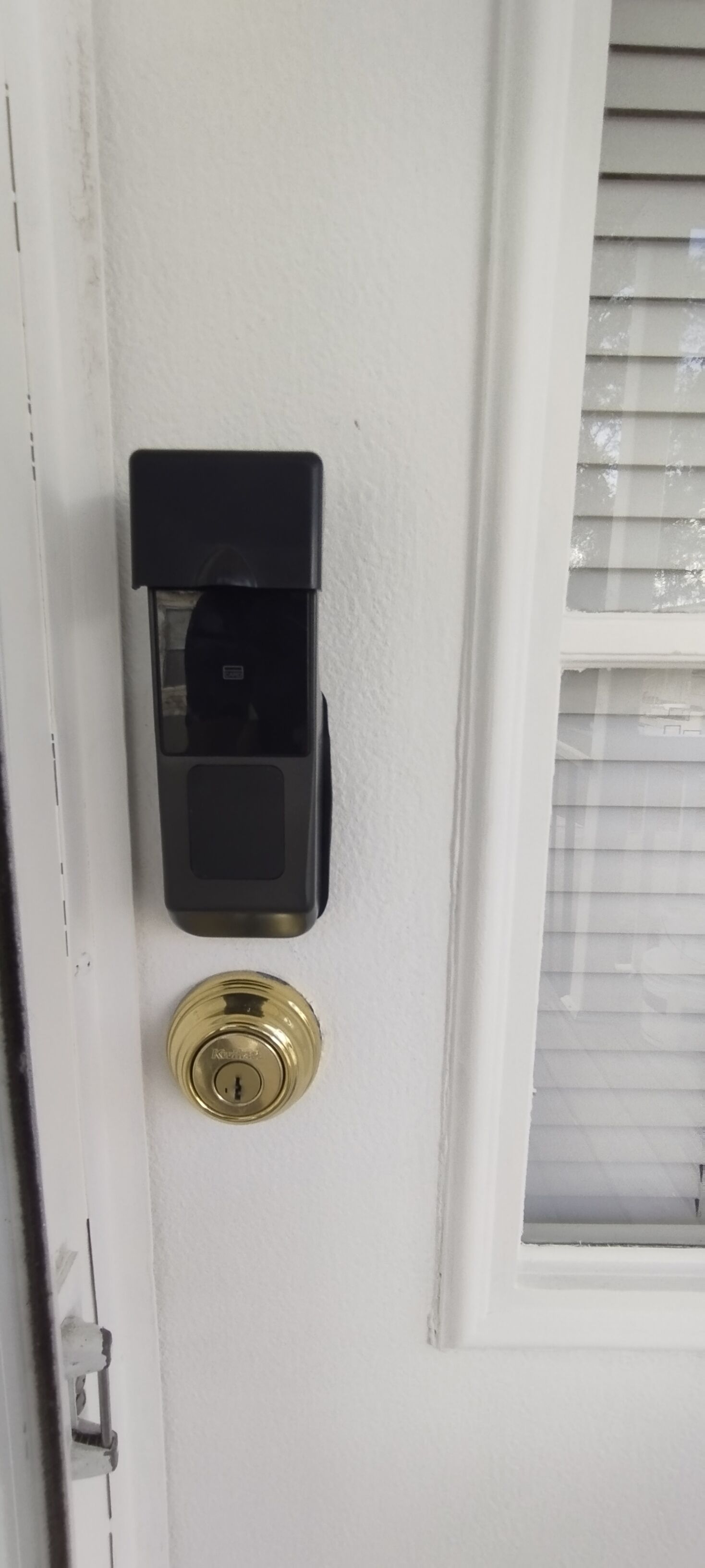 A door with a keypad lock and a window with blinds.