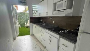 A modern kitchen with white cabinets, a granite countertop, and a built-in microwave.