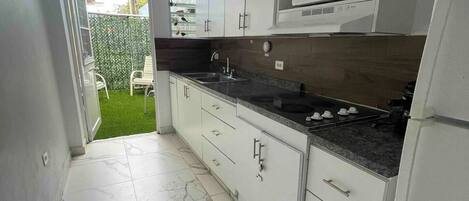 A modern kitchen with white cabinets, a granite countertop, and a built-in microwave.
