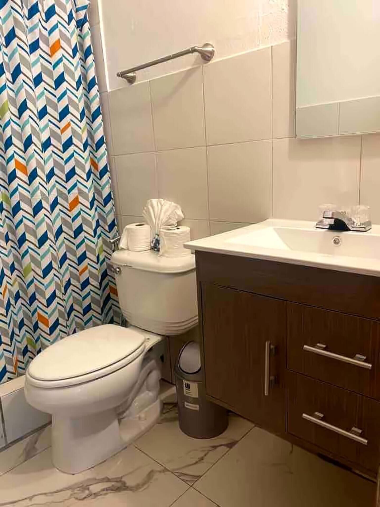 A bathroom with a white toilet, a sink, a mirror, and a shower curtain.