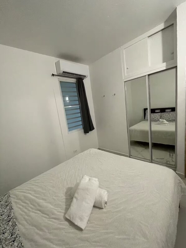 Ein Hotelzimmer mit einem Bett, einem Vorhangfenster, einem Kleiderschrank und einem Spiegel.
