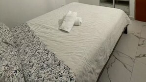 A hotel room with a bed, a window with curtains, a wardrobe, and a mirror.