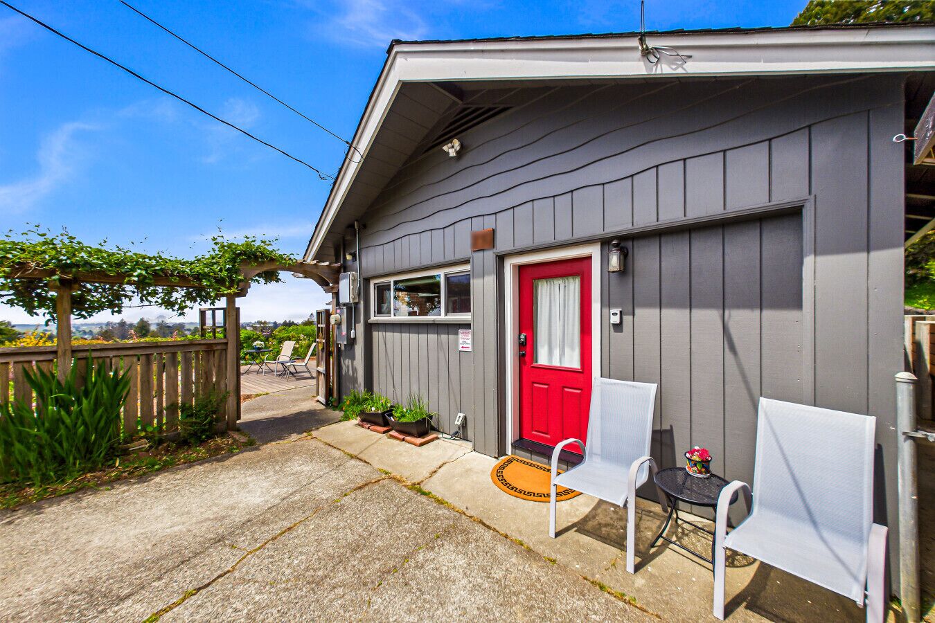 A small, single-story building with a red door and a covered porch area.
