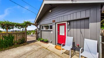 A small, single-story building with a red door and a covered porch area.