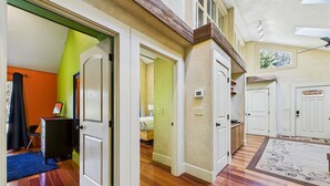 Un hall d’entrée spacieux, doté d’un parquet en bois, de portes blanches et d’un tapis bleu.