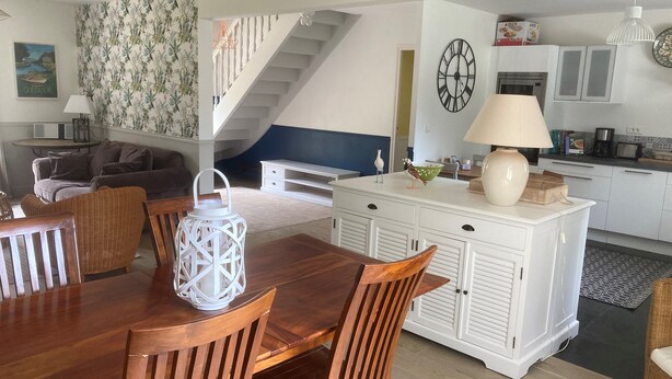 A spacious living area with a wooden dining table, comfortable seating, a staircase, and a kitchen area with modern appliances. - Large family home in Mesquer (Mesquer)