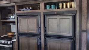 A kitchen with a built-in microwave, two stainless steel refrigerators, a sink, and a wooden bowl on the countertop. -  Port Saint Joe 1/1 Trailer that sleeps 4, only 2 blocks to Beach -Pet friendly! (Port St. Joe)