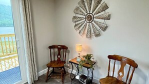 Une pièce d’angle comprenant deux chaises en bois, une petite table avec une lampe et un élément décoratif mural.