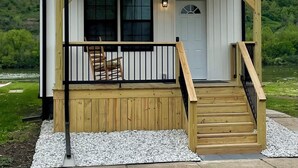 Une maison à deux étages avec un porche à l’avant, un escalier en bois et une porte dotée d’un panneau de verre.