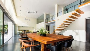 Un vaste espace dédié à la salle à manger, avec une table et des chaises en bois, un escalier avec des marches en bois et une rampe en verre.