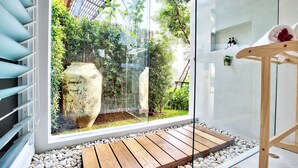 Un baño moderno con un ventanal grande, suelo de madera y un tendedero de madera.