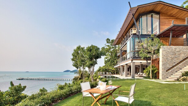 Una casa moderna con piscina, comedor y vista al mar.