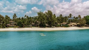 A beachfront property with multiple houses, a sandy beach, and a clear blue sea.