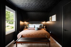 Une chambre avec un grand lit, des lampes de chevet, une fenêtre et une porte.