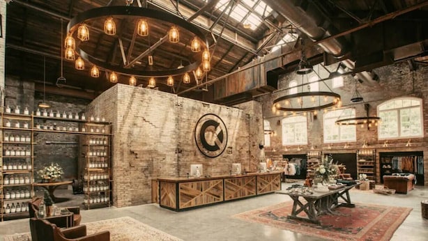 A spacious interior with exposed brick walls, a central wooden reception desk, and a large circular wall clock. - Bourbon Trail*River Views*Hot Tub*Sauna*EVSE*WiFi (Frankfort)