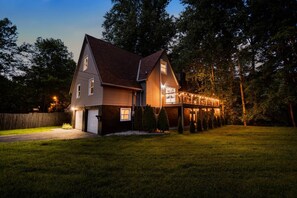 Une maison à deux étages avec un porche et des guirlandes lumineuses.