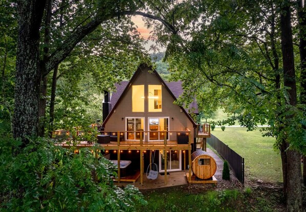 Une cabane dotée d’une terrasse, d’un bain à remous et d’une chaise suspendue.