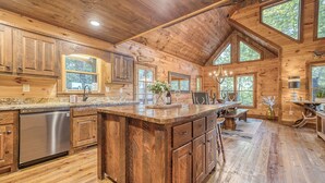 Un'ampia cucina con mobili in legno, una grande isola e un'area pranzo con tavolo e sedie.