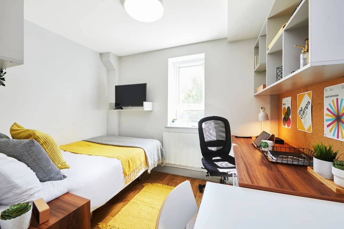 Une chambre moderne avec deux lits, un bureau, une chaise, une télévision et une fenêtre.