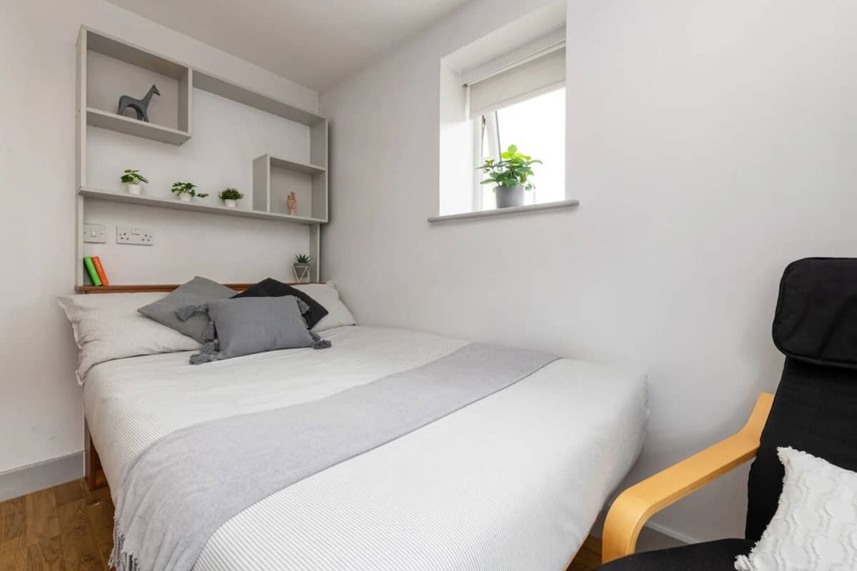 Une chambre moderne avec un lit, une chaise et des étagères intégrées ornées de plantes.