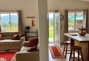 A living room with a sofa and a dining area with a table and stools.
