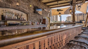 Un bar avec un comptoir en bois et des étagères remplies de bouteilles d’alcool.