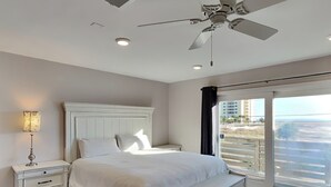 A bedroom with a bed, nightstands, a lamp, a ceiling fan, and a view through a large window. - Grande Belle by Southern Vacation Rentals (Navarre)