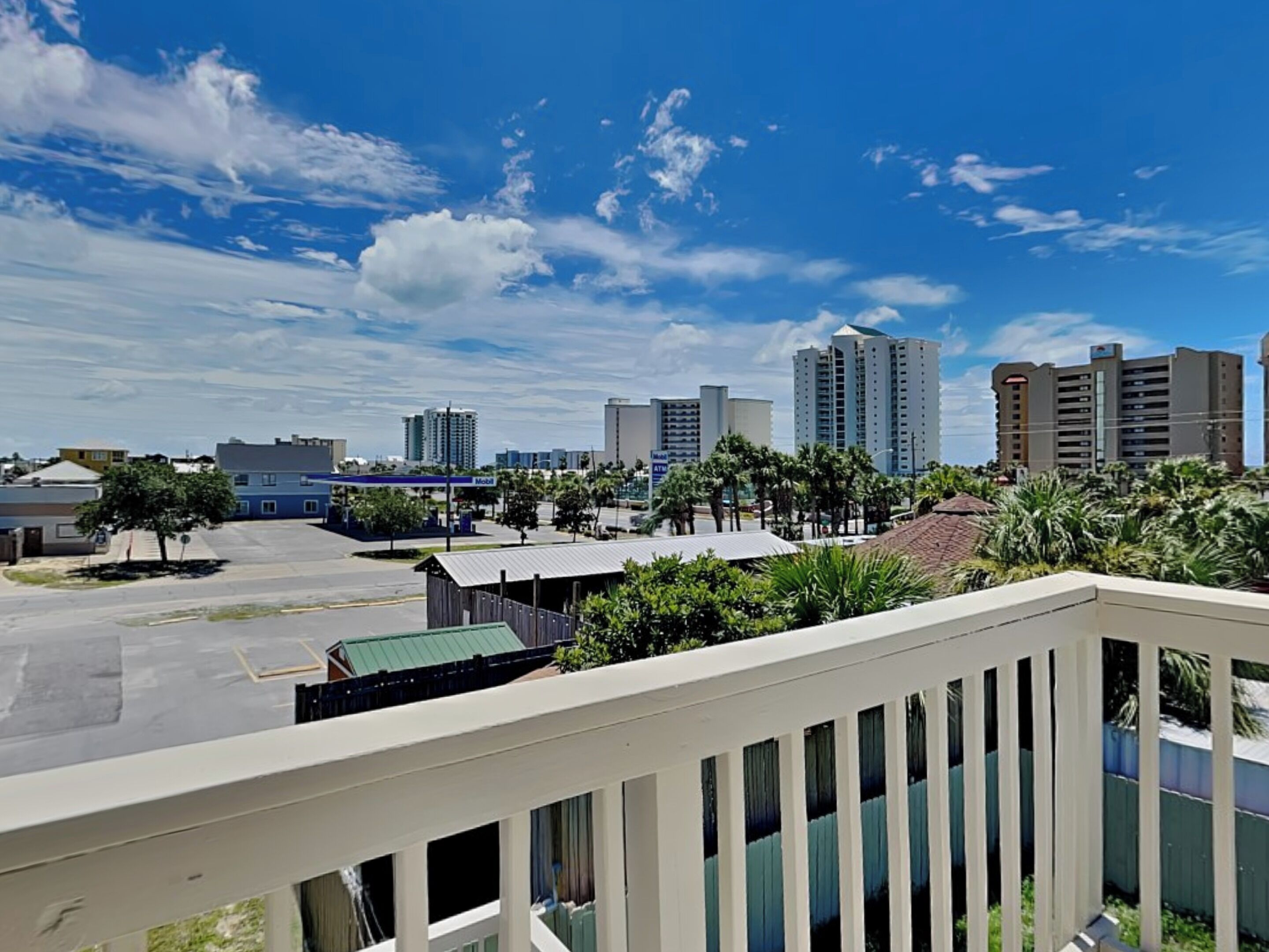 Paisagem urbana com edifícios altos, um estacionamento e um céu azul e límpido.