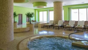 Un área de spa con jacuzzi, sillones reclinables y amplias ventanas.