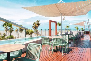 A deck with outdoor seating, a pool, and a view of the ocean.