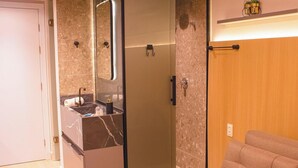 A bathroom with a marble sink, a mirror, a towel rack, and a wooden door. - Setai Yacht Premium II - By Almare Flats (João Pessoa)