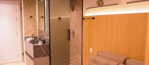 Un baño moderno con tocador de mármol, cabina de ducha de vidrio y pared de madera.