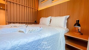 Camera d'albergo con un letto, comodino, lampada e parete rivestita in legno.