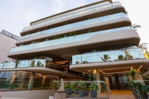 A modern building with multiple balconies, glass windows, and indoor plants.