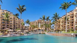 Ein Resort mit großem Pool, Palmen und mehrstöckigen Gebäuden.