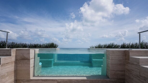A clear pool with a view of the ocean, surrounded by stone walls and metal railings. - Luxury Modern Beachfront Apartment - Incredible Sunrise and Sunset View (Puerto Morelos)