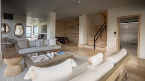 A spacious living area with a modern sofa set, a coffee table, and a staircase leading to an elevator. - Luxury Modern Beachfront Apartment - Incredible Sunrise and Sunset View (Puerto Morelos)