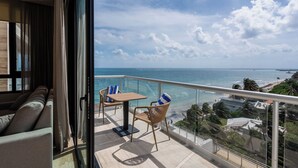 A balcony with a view of the ocean, a table, and two chairs. - Luxury Modern Beachfront Apartment - Incredible Sunrise and Sunset View (Puerto Morelos)