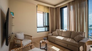 A living room with a sofa, armchairs, a small table, and a TV. - Luxury Modern Beachfront Apartment - Incredible Sunrise and Sunset View (Puerto Morelos)